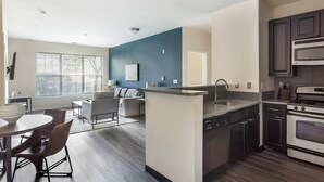 A modern kitchen with a central island, built-in appliances, and a dining area with a table and chairs. - Landing | Incredible 2BD, Pool, Gym (King of Prussia)