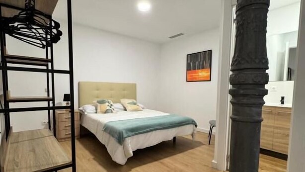 A bedroom with a bed, a wooden bunk bed, a mirror, and a dark pillar. - Apartamentos Melisa (Madrid)