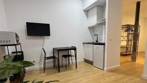 A modern living area with a flat-screen TV, a small kitchen, and a dining table. - Apartamentos Melisa (Madrid)