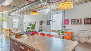 A spacious kitchen with a large island, wooden cabinets, and pendant lighting. - Bright and airy loft space 10 min walk from stadiums with private roof terrace (Atlanta)