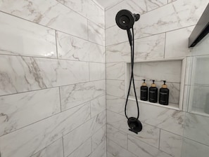Eine Dusche mit Handbrause und Armaturen an der Wand.