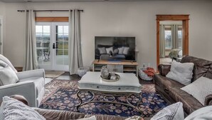 Ett vardagsrum med en tv, ett soffbord, en soffa och en mönstrad matta.