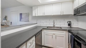 A modern kitchen with white cabinets, a stainless steel sink, and a built-in oven. - Landing | Modern 1BD in Glendale (Glendale)