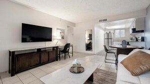 A modern living room with a flat-screen TV, a dark wood console, a white coffee table, and a brown cushion. - Landing | Incredible 2BD in Glendale (Glendale)