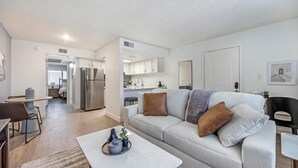 A modern living room with a sofa, coffee table, and a kitchen in the background. - Landing | Incredible 1BD in Glendale (Glendale)