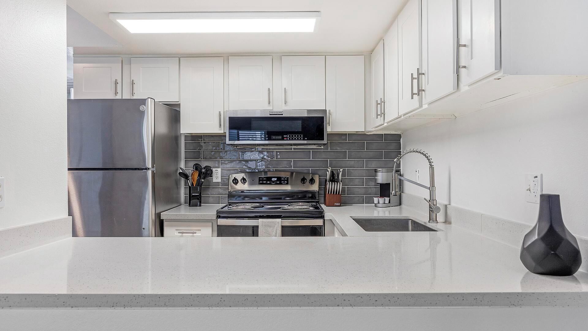 Een moderne keuken met roestvrijstalen apparatuur, een magnetron en een gasfornuis.