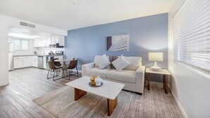 Ein modernes Wohnzimmer mit einer Couch, einem Couchtisch und einem Essbereich mit Stühlen.