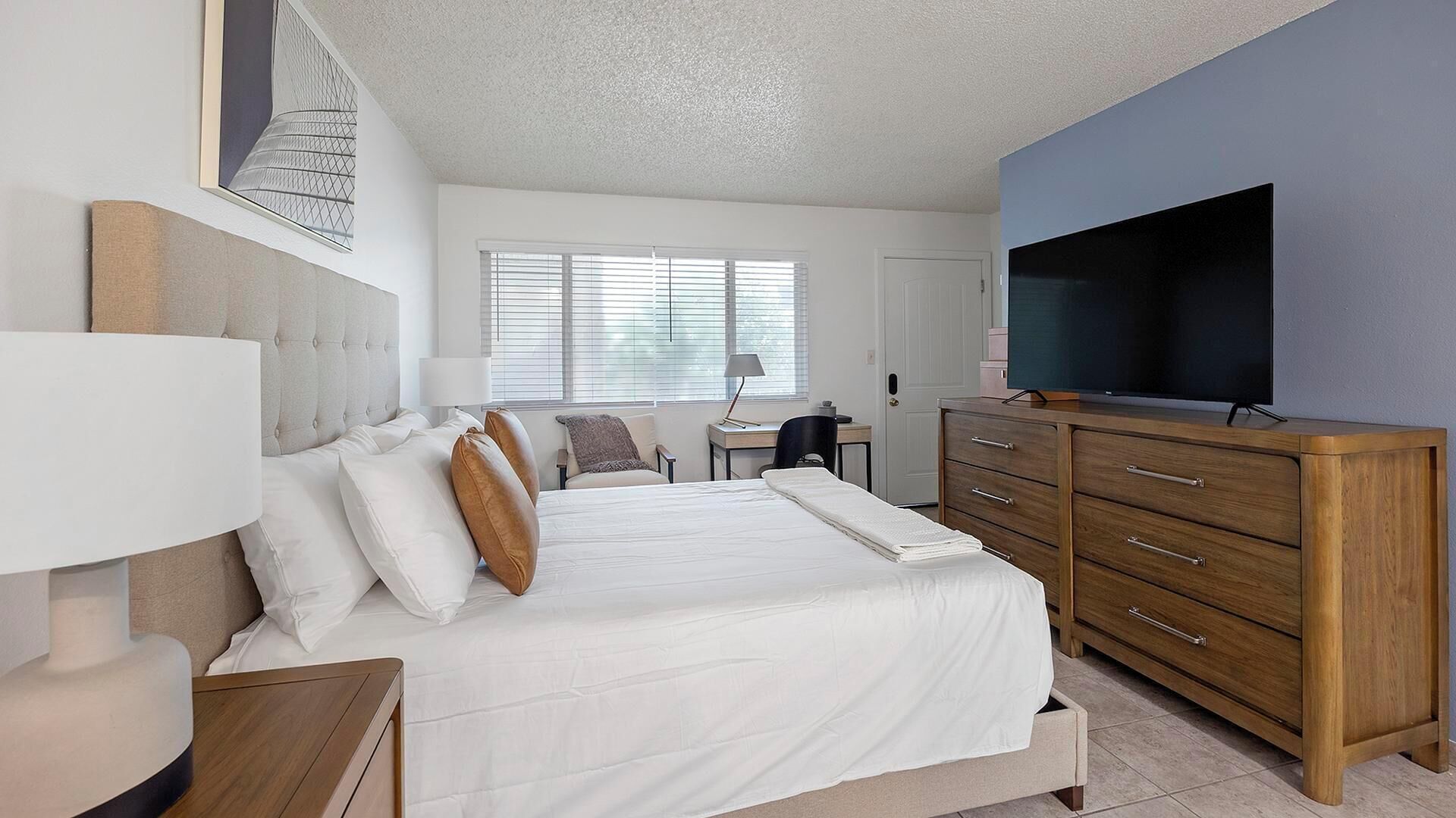 Une chambre à coucher avec un lit, une télévision, un bureau et une commode.