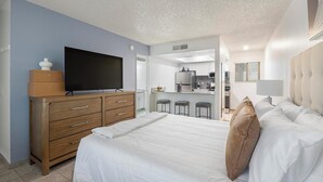 Ein Schlafzimmer mit Bett, einem Fernseher auf einer Kommode, einer Küchenzeile und einem Badezimmer.