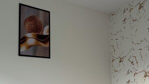 A bedroom with a bed, a ceiling fan, a wall-mounted artwork, and a textured wall. - Cozy apartment (Salvador)
