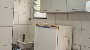 A compact kitchen with white cabinets, a sink, and a refrigerator. - Cozy apartment (Salvador)