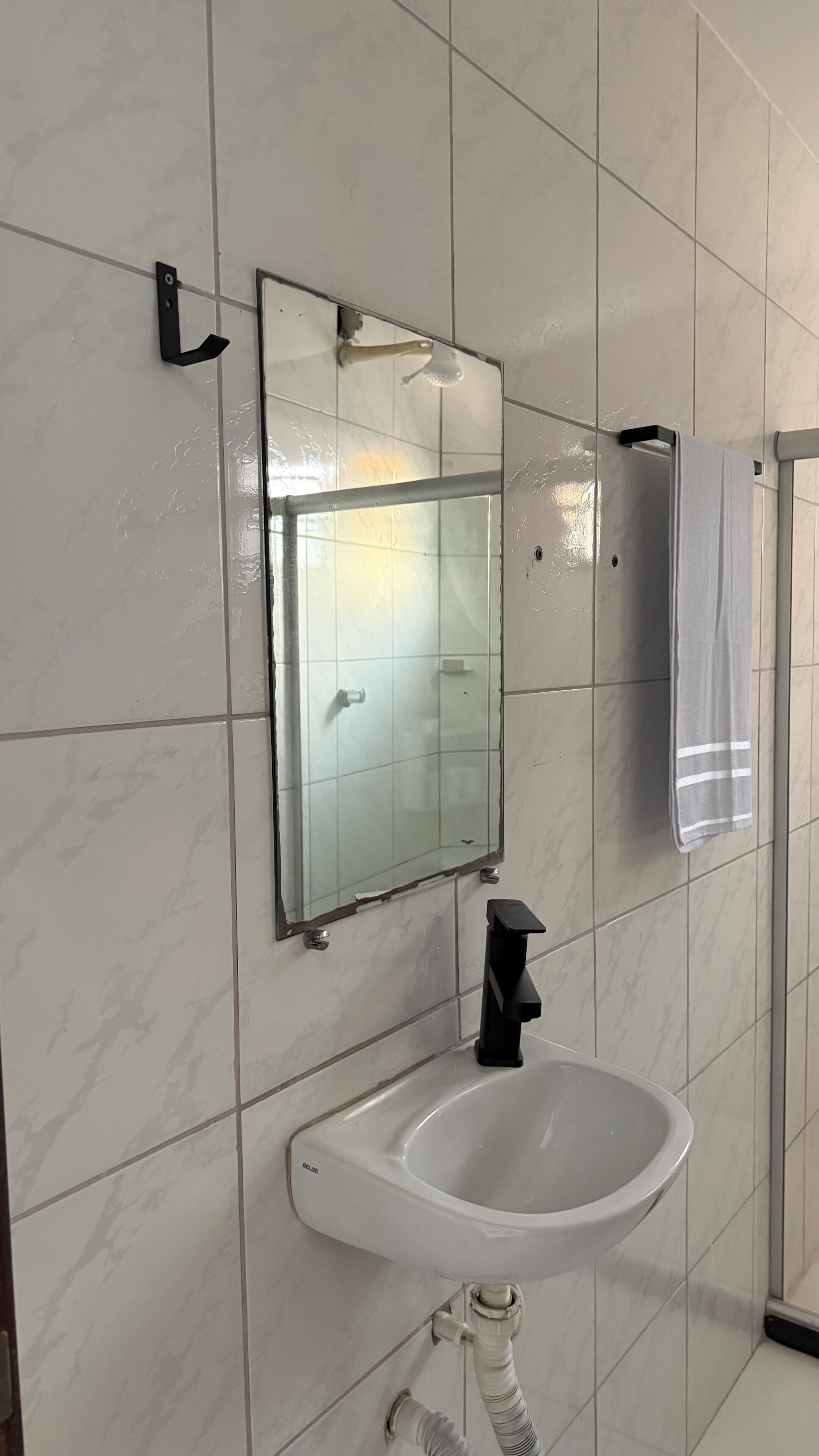 Ein Badezimmer mit Waschbecken, Spiegel und Handtuchhalter.