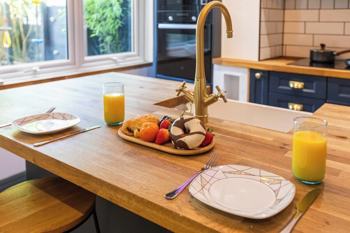 Een keukentafel met een ontbijtje, inclusief een bord gebak, een glas sinaasappelsap en een ander glas sap.