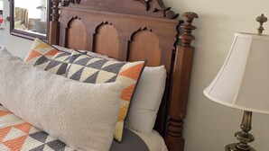 A bed with a patterned quilt, pillows, and a wooden headboard. - The Lone Start Suite on the Mississippi River in Donaldsonville (Donaldsonville)