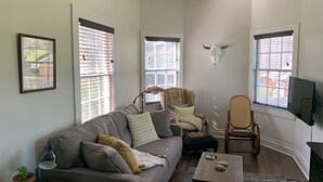 A living room with a sofa, armchairs, a coffee table, a TV, and a bull skull decoration. - The Lone Start Suite on the Mississippi River in Donaldsonville (Donaldsonville)