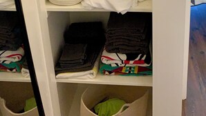 A closet with hanging clothes, a basket, folded clothes, and storage bins. - The Lone Start Suite on the Mississippi River in Donaldsonville (Donaldsonville)