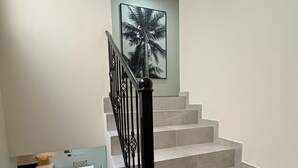 Uma escadaria com guarda-corpo preto que leva a um patamar com cozinha.