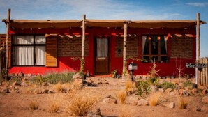 A rustic building with a red facade, wooden beams, and a covered porch. - Ranchito de Montaña a refuge designed for unique moments Casita close to everything (Lujan De Cuyo)