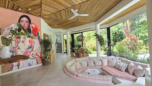 Interior moderno com um mural grande, uma área de estar circular e vista para vegetação exuberante lá fora.