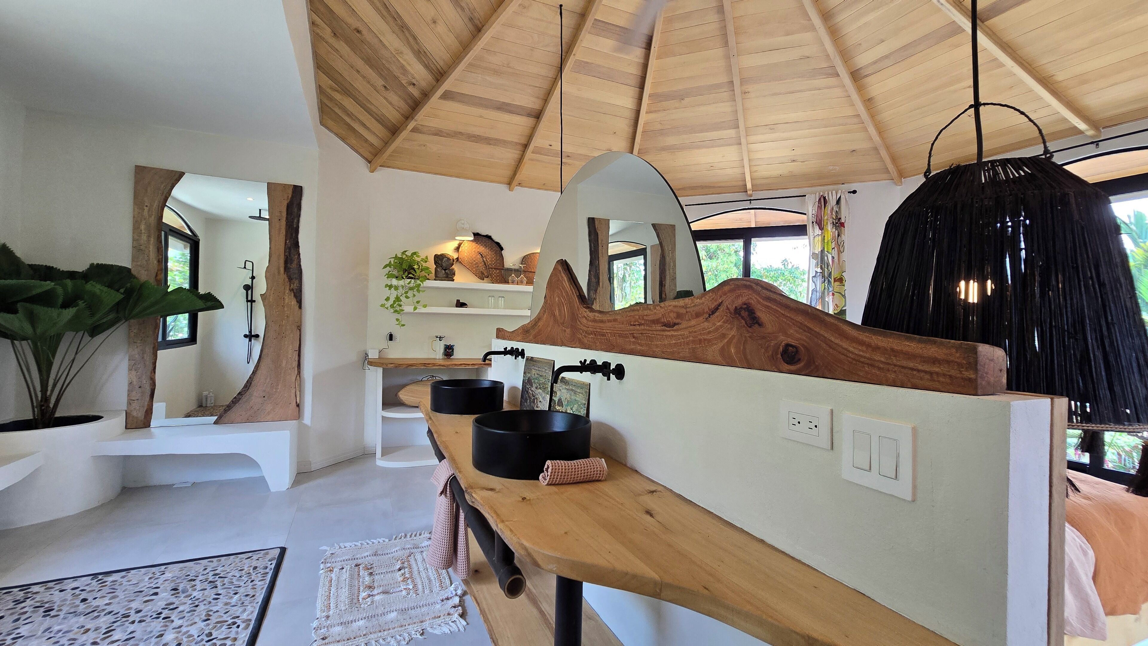 A modern kitchen with wooden countertops, black sinks, and a large mirror.