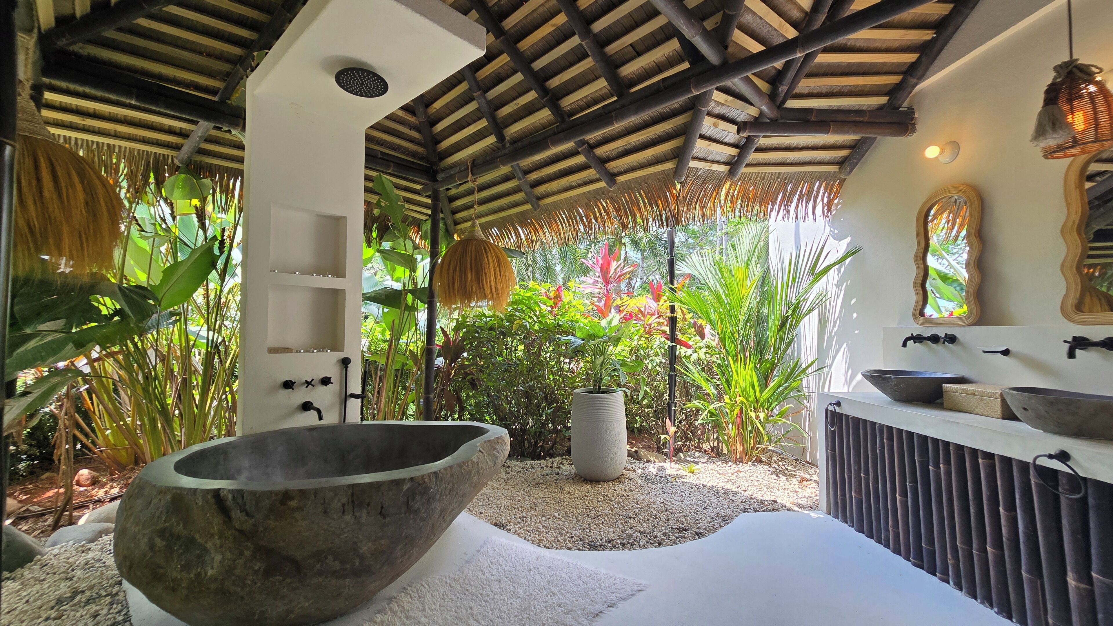 A bathroom with a large stone basin, a white sink, and a mirror.