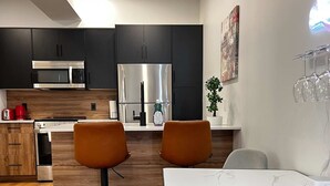 Una cucina moderna con mobili scuri, elettrodomestici in acciaio inossidabile e pavimento in legno.