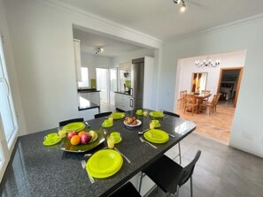 A modern kitchen with a dining table set for six, equipped with a refrigerator, oven, and ample counter space. - Villa Heartly – Luxury, Tranquillity & Panoramic Sea Views (Playa Blanca)