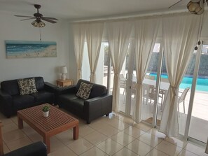 A living room with two sofas, a coffee table, and a ceiling fan. - Villa Heartly – Luxury, Tranquillity & Panoramic Sea Views (Playa Blanca)