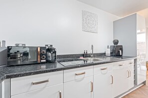 Uma cozinha moderna com fogão a gás, cafeteira e pia.