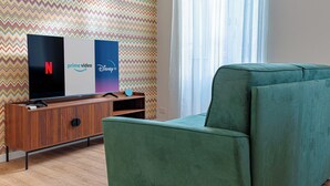Ein Wohnzimmer mit Flachbildfernseher, einer Holzunterhaltungsecke, einem grünen Sofa und einer Wand mit Zickzackmuster.