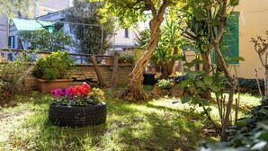 Ein Garten mit einem Reifenbeet, Bäumen und einem Gebäude im Hintergrund, das einen grünen Rollo hat.