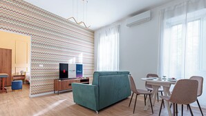 Ein modernes Wohnzimmer mit einer Couch, einem Esstisch, Stühlen und einem Fernseher.