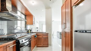 A modern kitchen with wooden cabinets, a stainless steel stove, and a refrigerator.