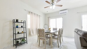 A dining area with a table and chairs, a ceiling fan, and a black shelving unit with plants.