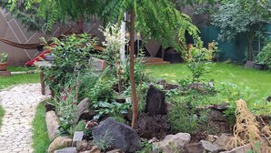 A garden with a stone pathway, a hammock, and various plants. - „Modern apartment 5 min from metro Anděl – fast WiFi“ (Praha)