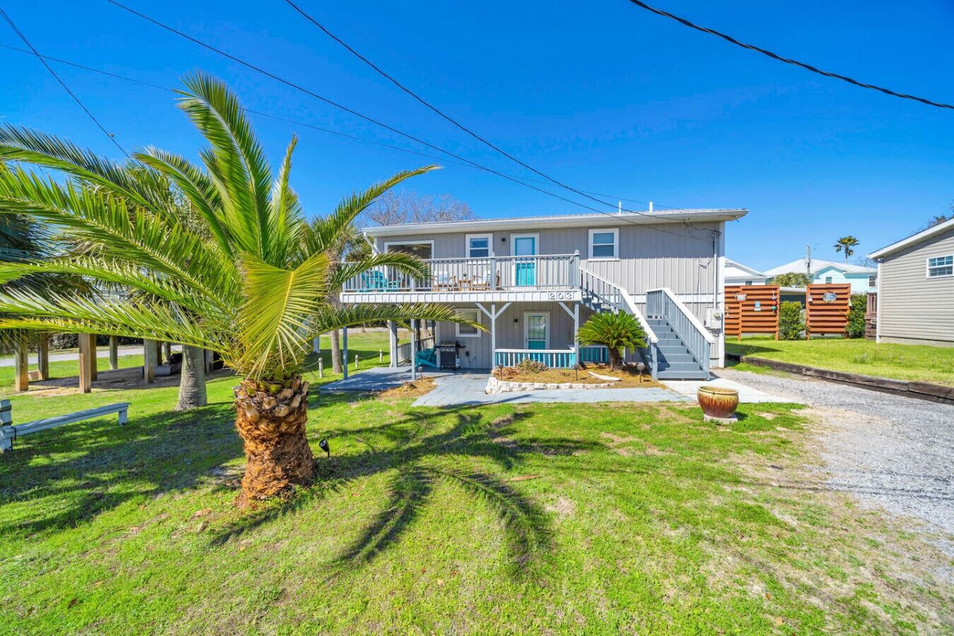 A two-story house with a covered porch, a staircase, and a palm tree in the foreground.