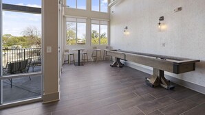 A spacious room with a pool table, large windows, and a view of the outdoors. - Landing | Modern 1BD, Clubhouse, Pool (Nashville)