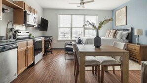 Eine kompakte Küche mit modernen Geräten, ein Essbereich und ein Schlafzimmer mit großem Fenster.