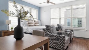 Quarto com cama, mesa de cabeceira, escrivaninha, cadeira e janela com persianas.