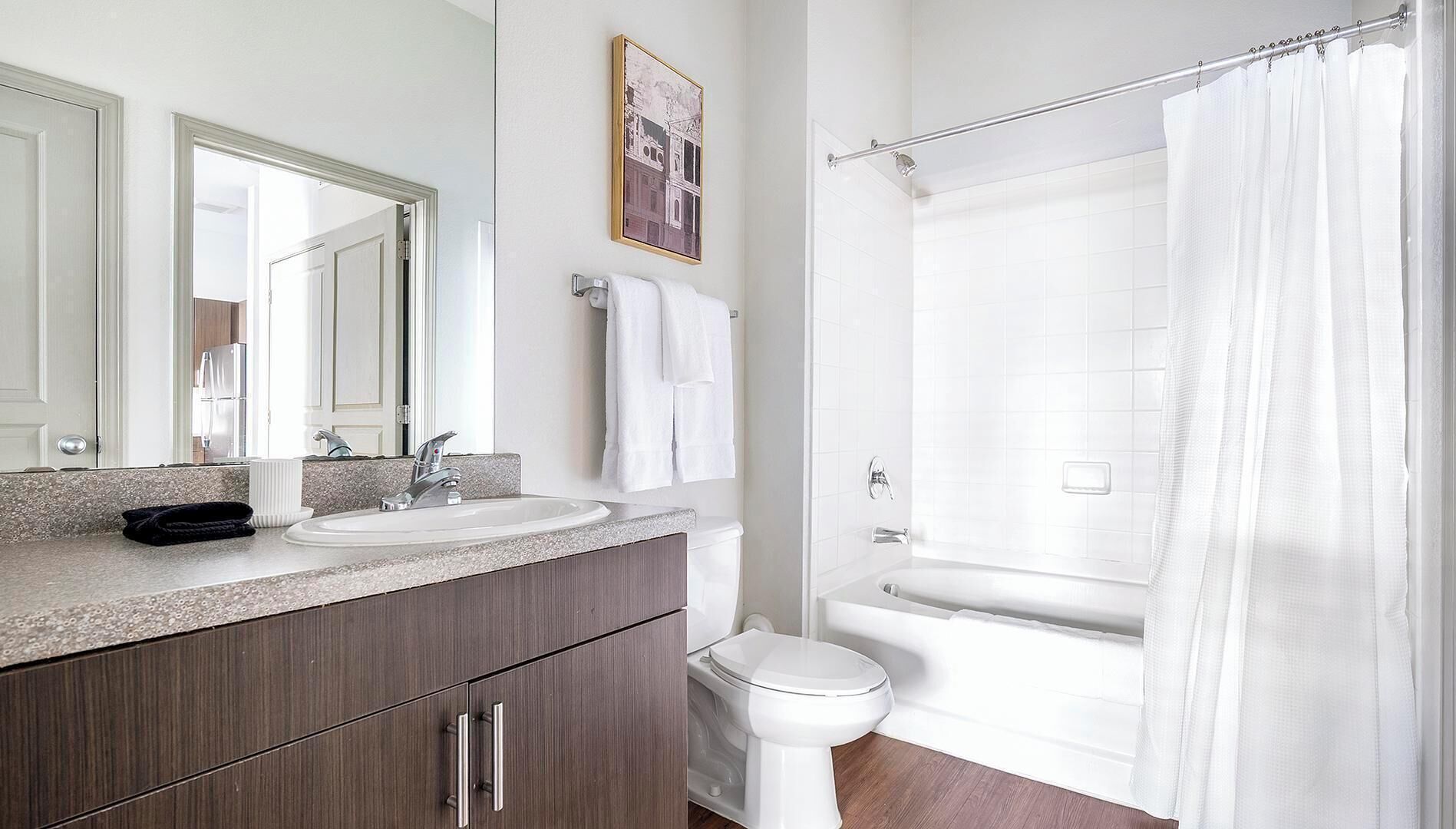 A bathroom with a sink, mirror, towel rack, toilet, and bathtub.