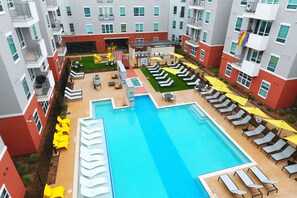 A rooftop pool area with multiple lounge chairs and umbrellas, surrounded by apartment buildings. - Landing | Stylish 2BD, Gym, Clubhouse (Arlington)