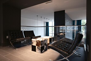A modern lounge area with leather chairs, a unique coffee table, and large windows offering a view of the city. - Landing | Amazing 2BD, Gym, Clubhouse (Arlington)