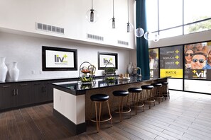 A modern kitchen with a central island, bar stools, and framed artwork on the wall. - Landing | Amazing 2BD, Gym, Clubhouse (Arlington)