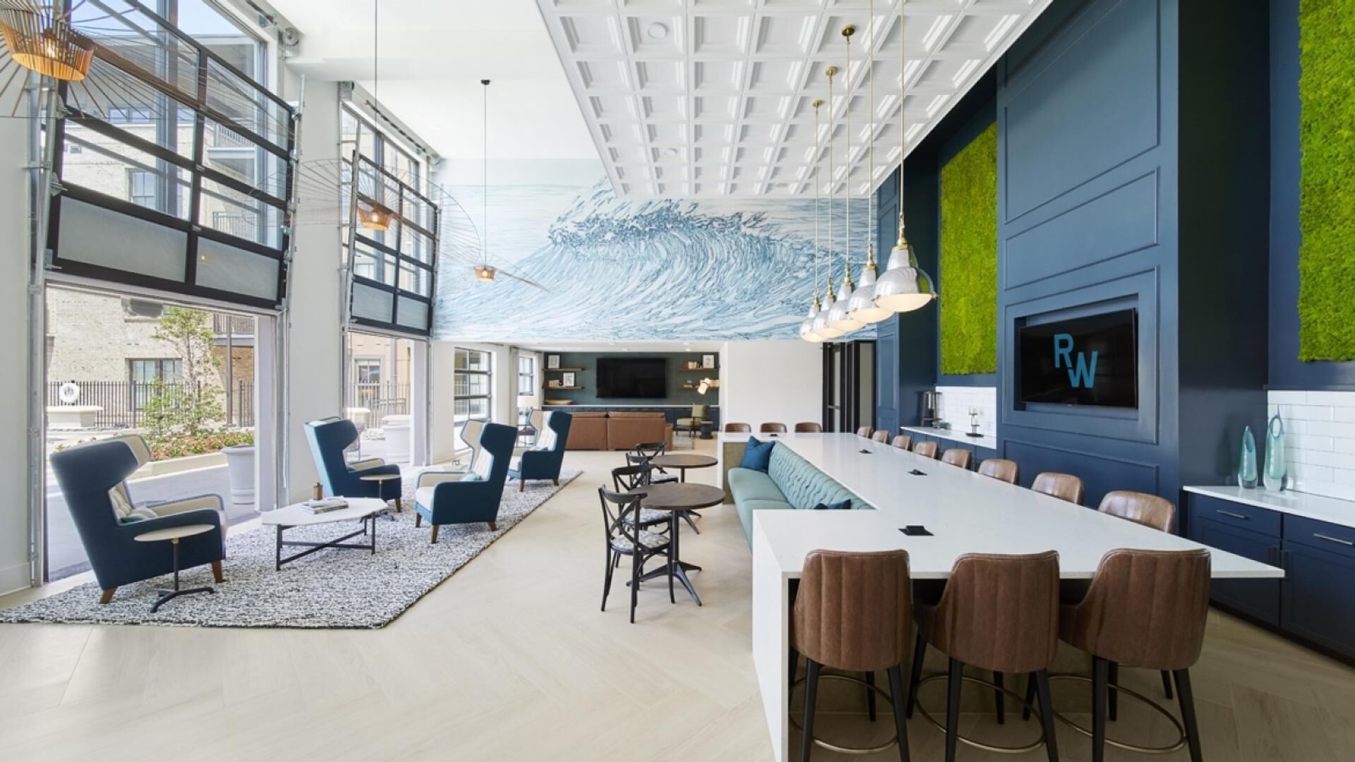 A modern office space with a long conference table, comfortable seating, and a large TV screen.