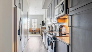 Una cocina moderna con electrodomésticos de acero inoxidable, encimera de madera y vista a una sala de estar.