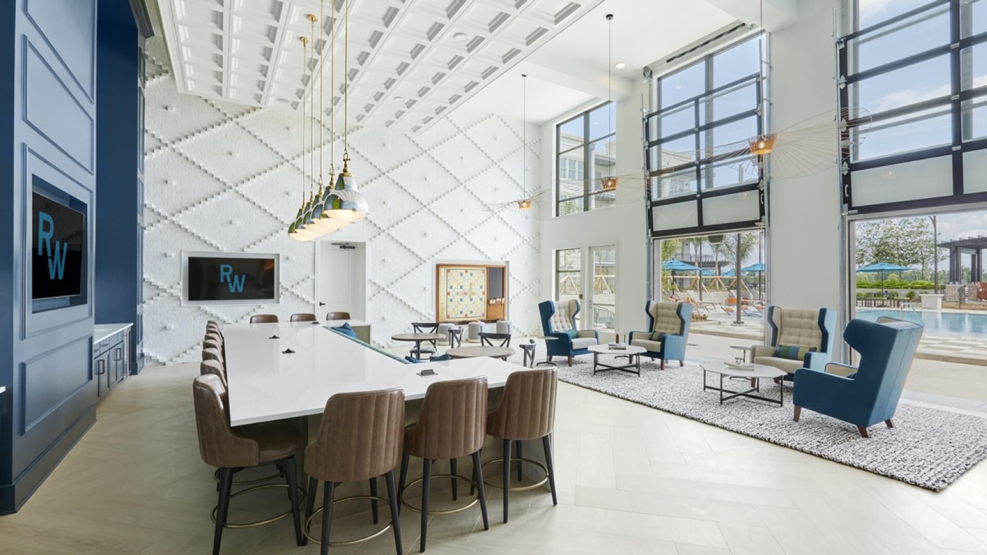 A modern hotel lobby with a large white reception desk, comfortable seating, and large windows offering views of the outdoor pool area.