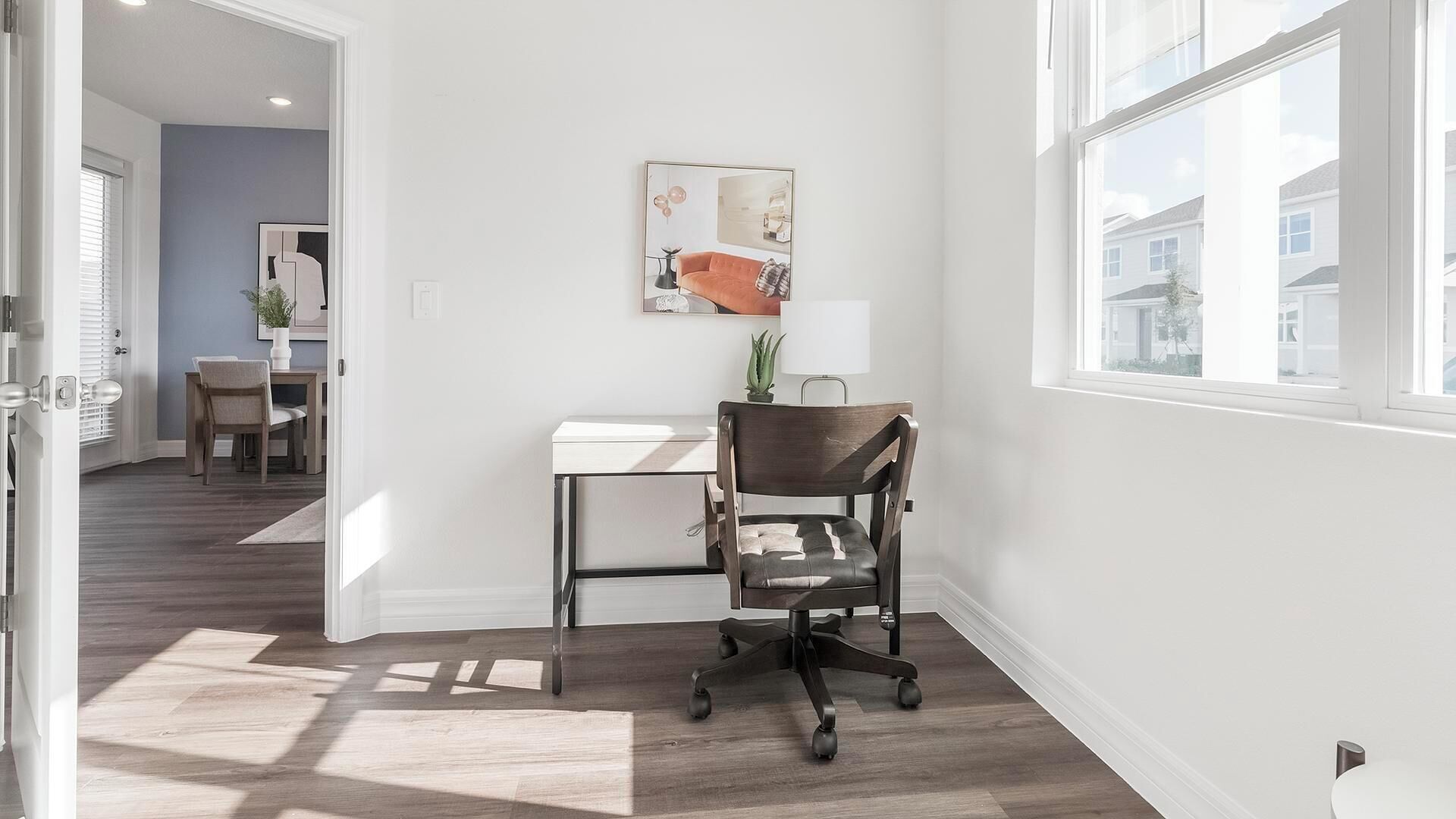 Una habitación con un escritorio, una silla y un ventanal grande.