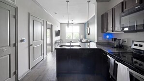 Een moderne keuken met een centraal kookeiland, inbouwapparatuur en uitzicht op de buitenruimte.