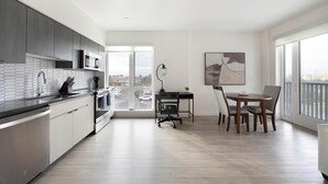 A modern kitchen with a dining area, large windows, and a view of the outside. - Landing | Spectacular 2BD, Pool, Yoga Studio (Tempe)