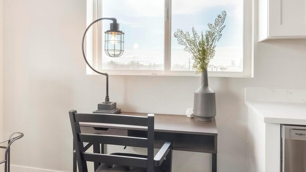 A desk with a chair, a lamp, a vase with flowers, and a window with a view. - Landing | Amazing 2BD in Harvey Park South (Englewood)